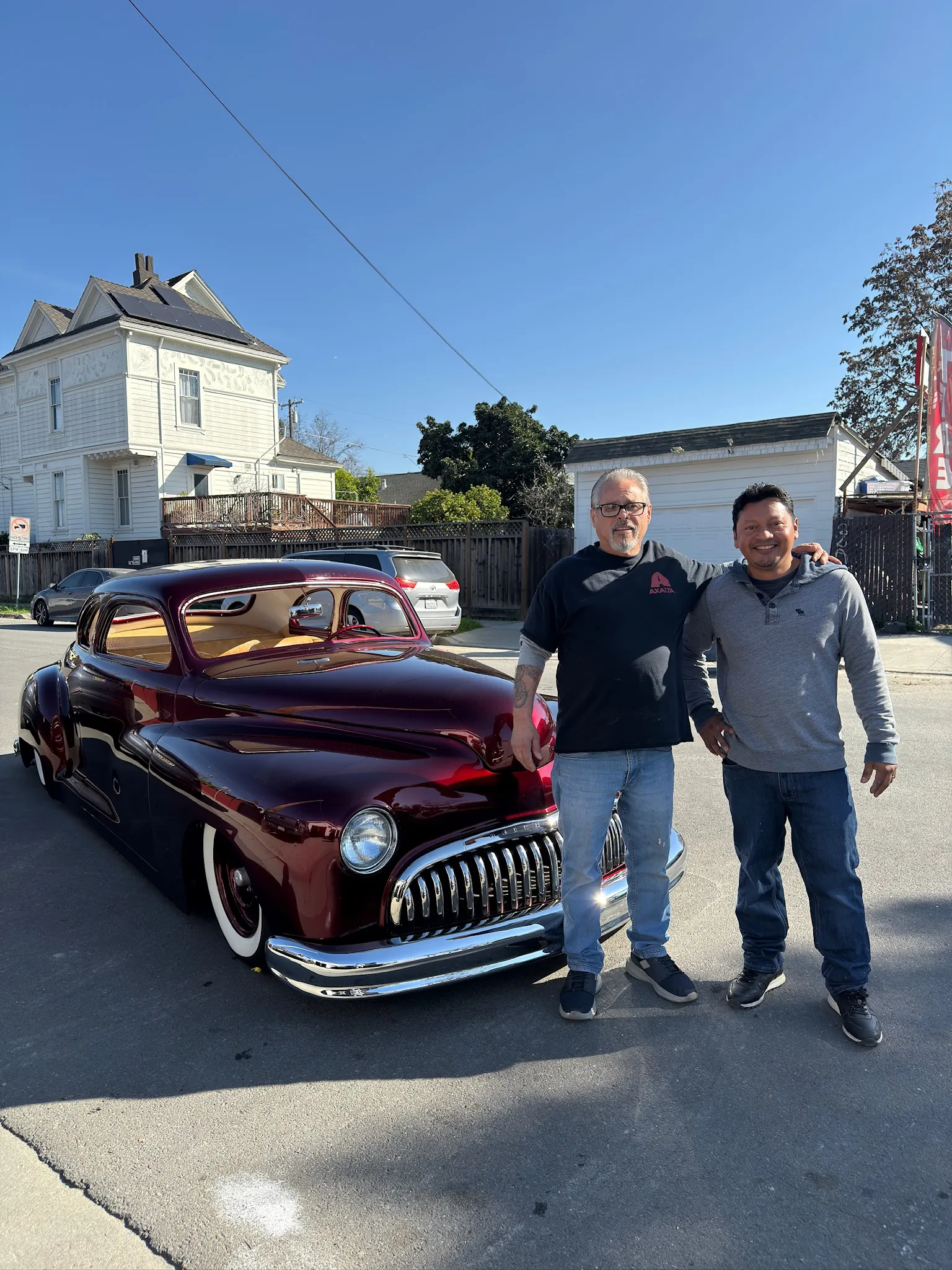Customer and shop owner with restored Buick Eight outside the shop.