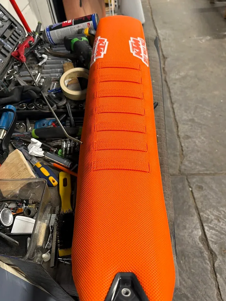 Orange KTM motorcycle seat top view with stitched pad sections.
