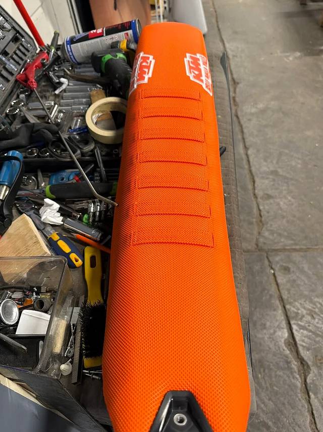 Orange KTM motorcycle seat top view with stitched pad sections.