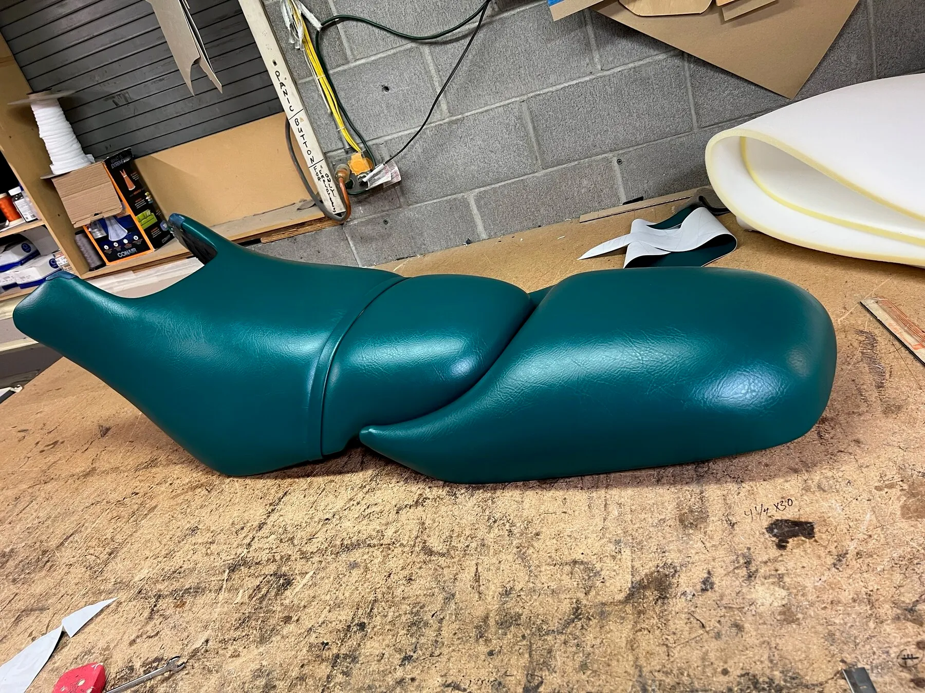 Green motorcycle seat upholstery on workbench.