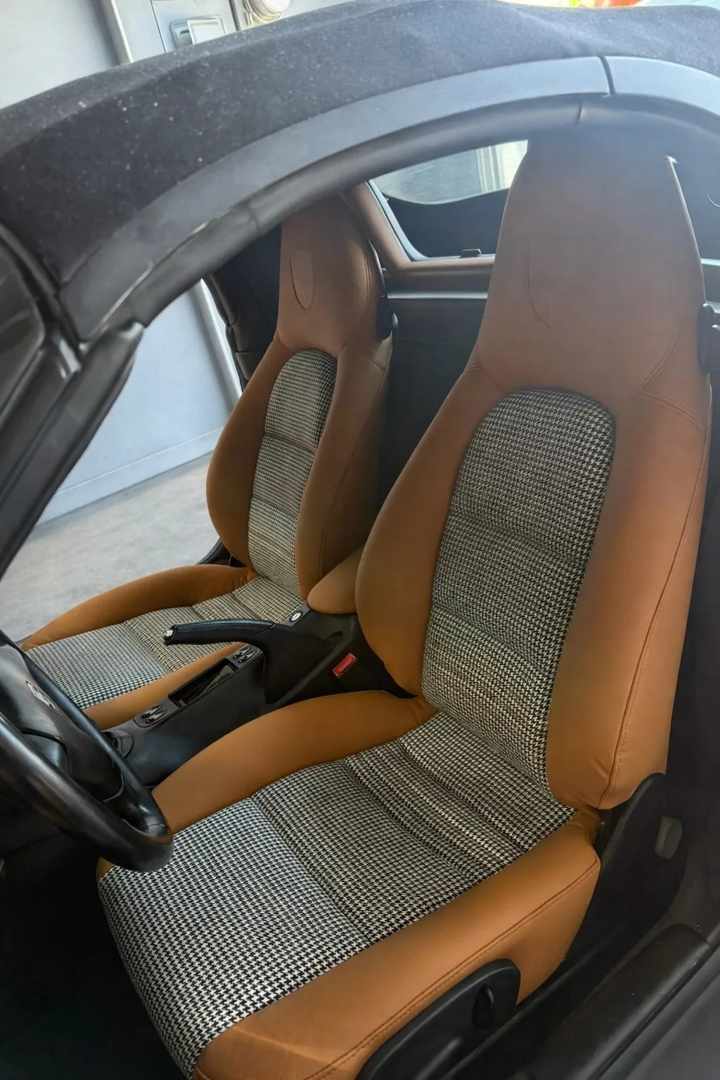 Close view of Porsche Boxster S front seats showing houndstooth centers and saddle leather bolsters.