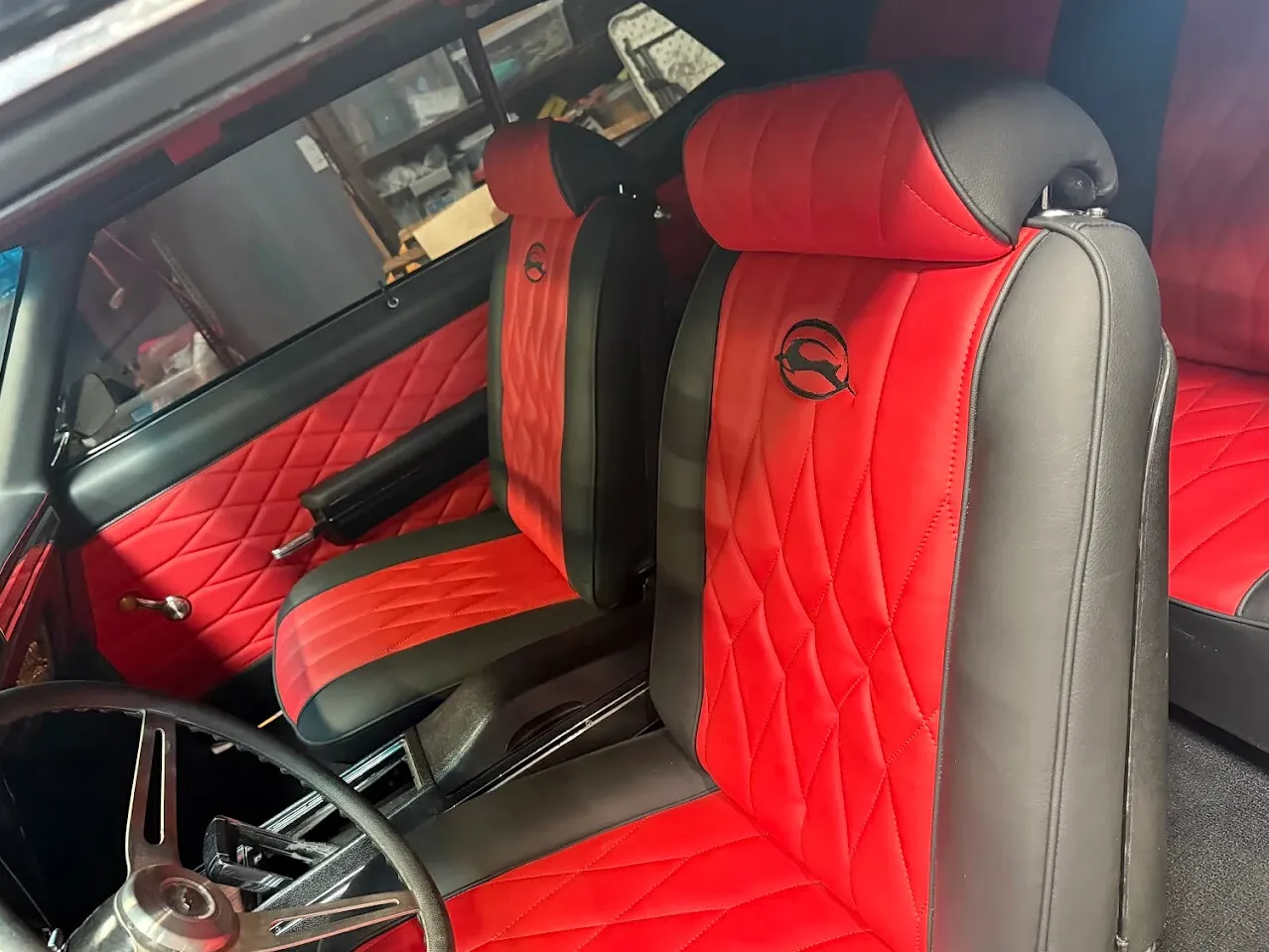 Red and black classic car front seats and door panel upholstery.